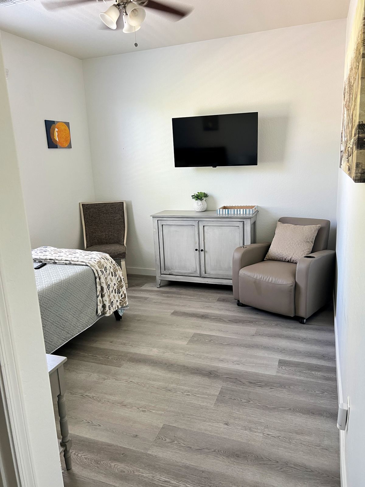 Resident room with wall-mounted television and chair